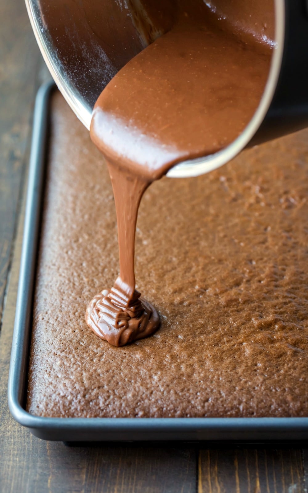 Icing pouring onto chocolate sheet cake