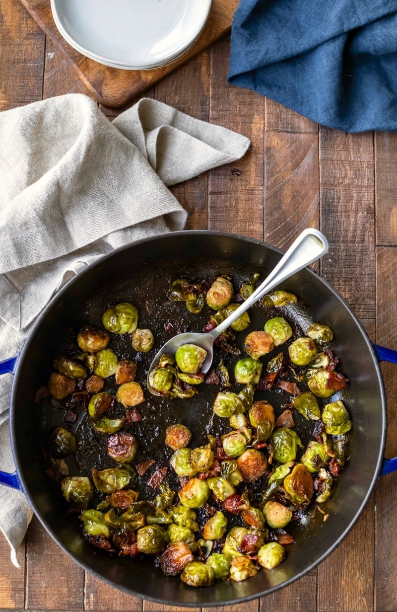 Maple bacon balsamic brussels sprouts in a cast iron pan with a silver spoon