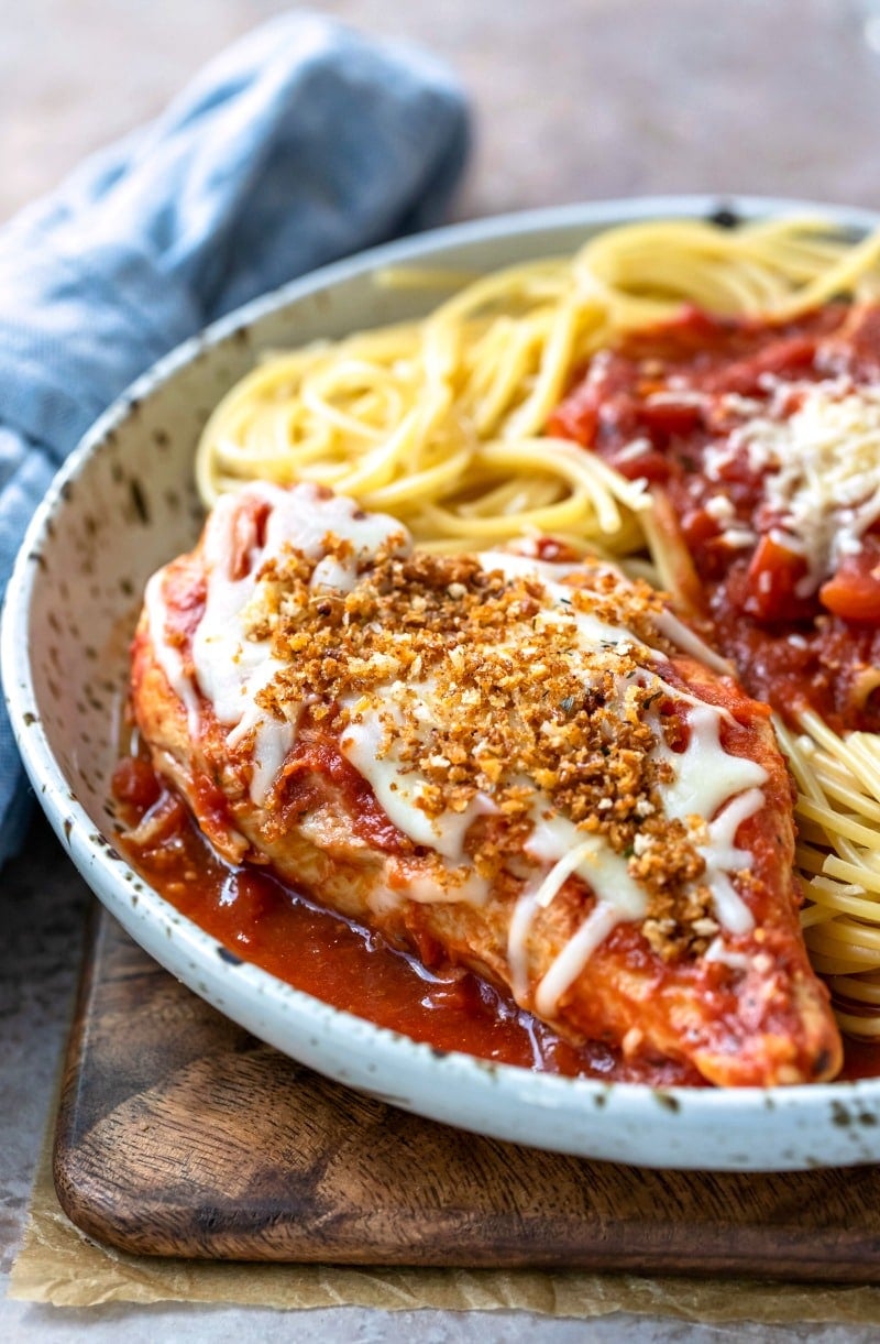 Plate with crock pot chicken parmesan topped with cheese and bread crumbs