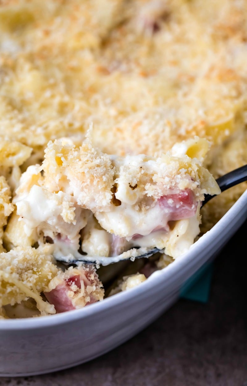 Scoop of chicken cordon bleu casserole coming out of a white baking dish