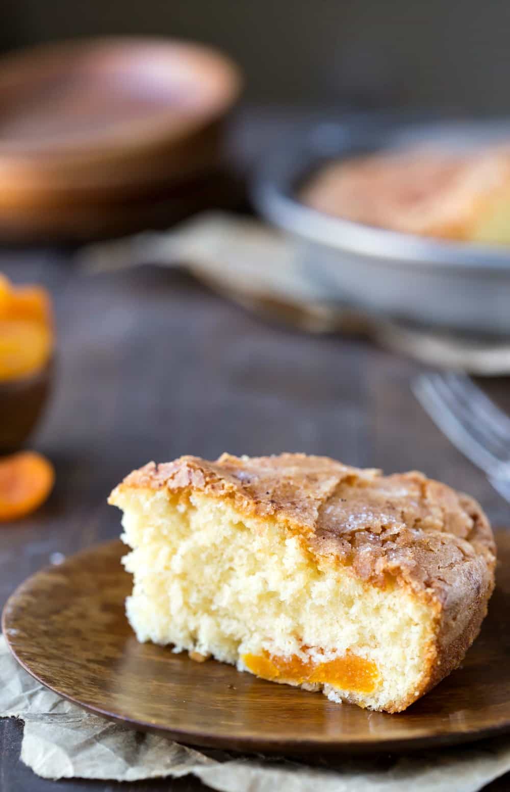 Slice of Apricot Kuchen on a wooden plate.