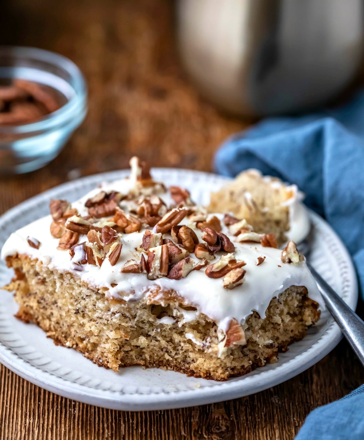 Slice of banana cake next to a blue linen napkin