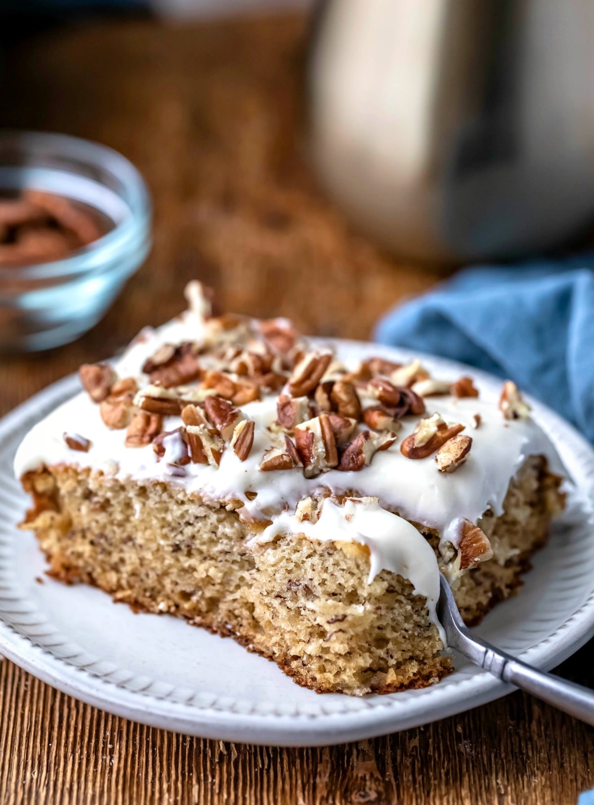 Banana Cake with Cream Cheese Frosting on a white plate with a silver fork