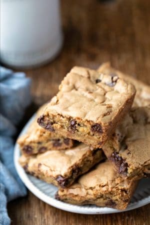 Stack of Chewy Chocolate Chip Cookie Bars on a plate next to a glass of milk