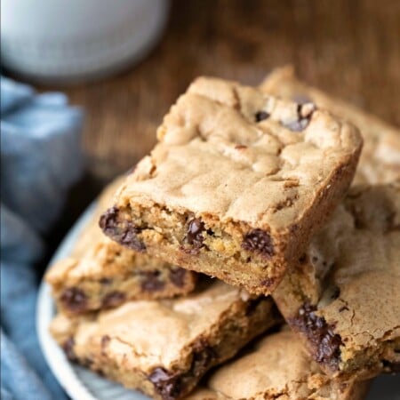 Stack of Chewy Chocolate Chip Cookie Bars on a plate next to a glass of milk