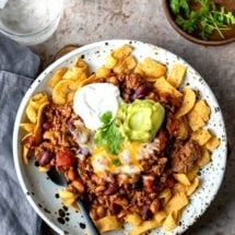 Plate of frito chili pie topped with sour cream and guacamole
