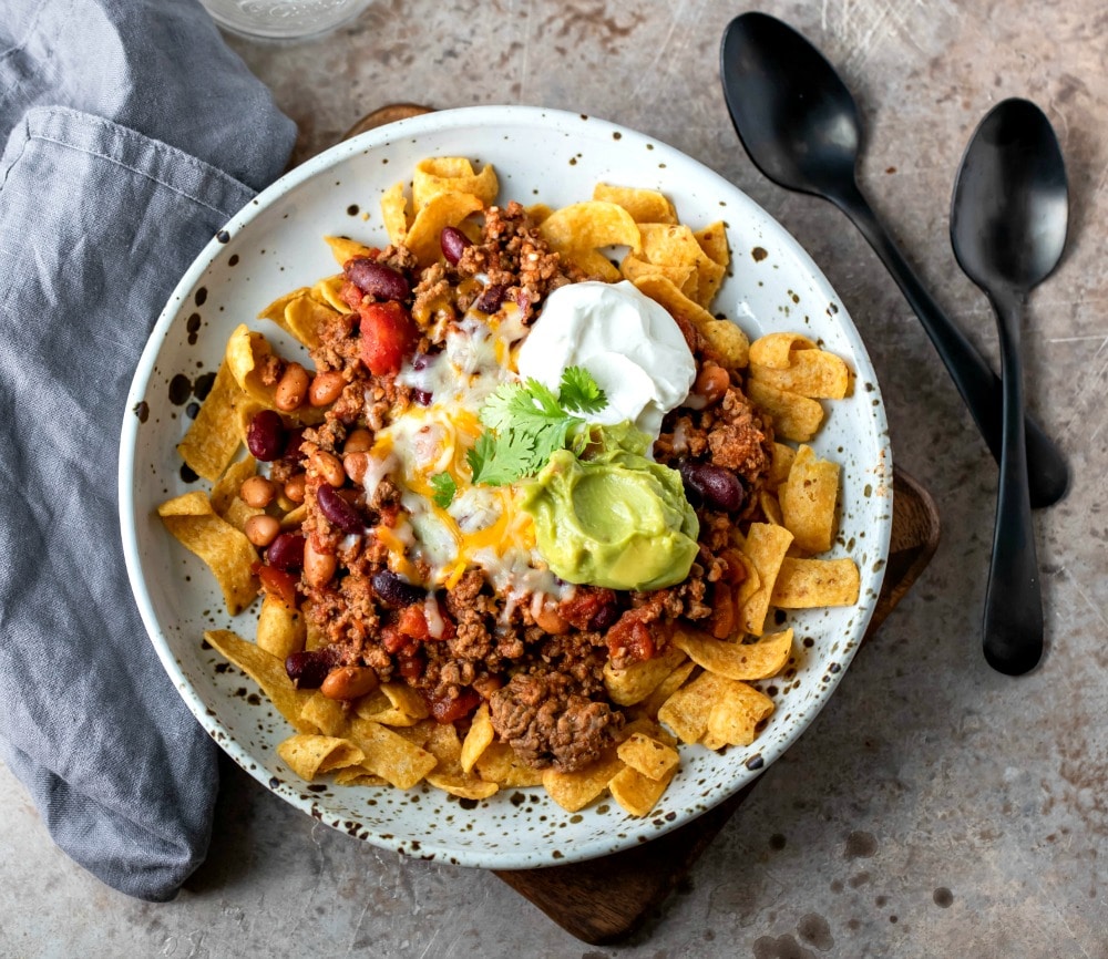 Frito Chili Pie Recipe Frito chili pie on a brown speckled plate