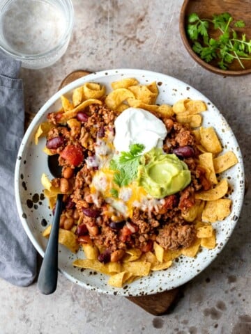 Frito chili pie on a plate with a black spoon in it