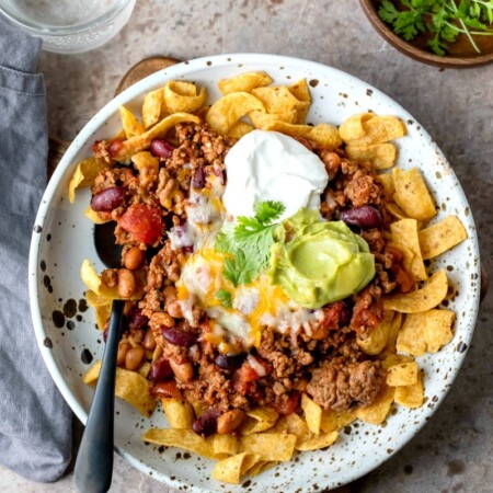 Frito chili pie on a plate with a black spoon in it