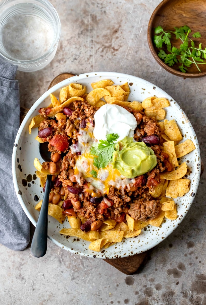 Frito chili pie on a plate with a black spoon in it