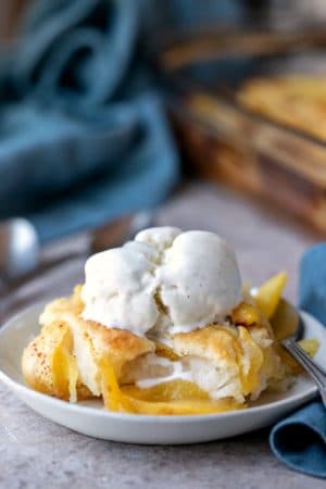 Dish of peach cobbler topped with a scoop of vanilla bean ice cream