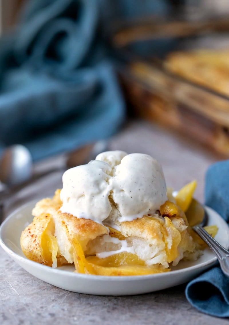 Dish of peach cobbler topped with a scoop of vanilla bean ice cream