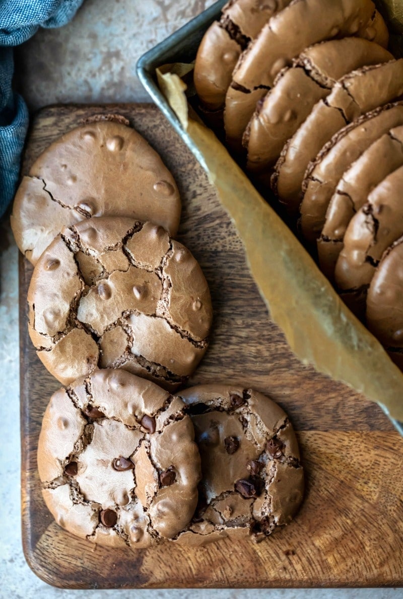 Row of flourless fudge cookies next to a tin of cookies