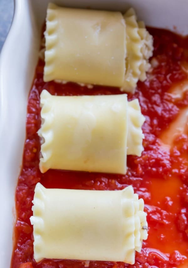 Three lasagna roll ups in a pan of sauce