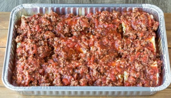 Meat sauce on top of Lasagna Roll-Ups in a silver baking dish