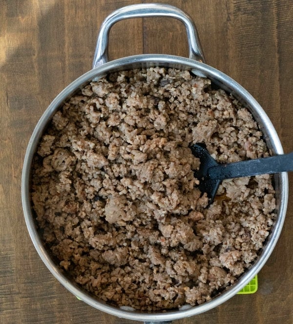 Silver skillet with browned ground beef in it.