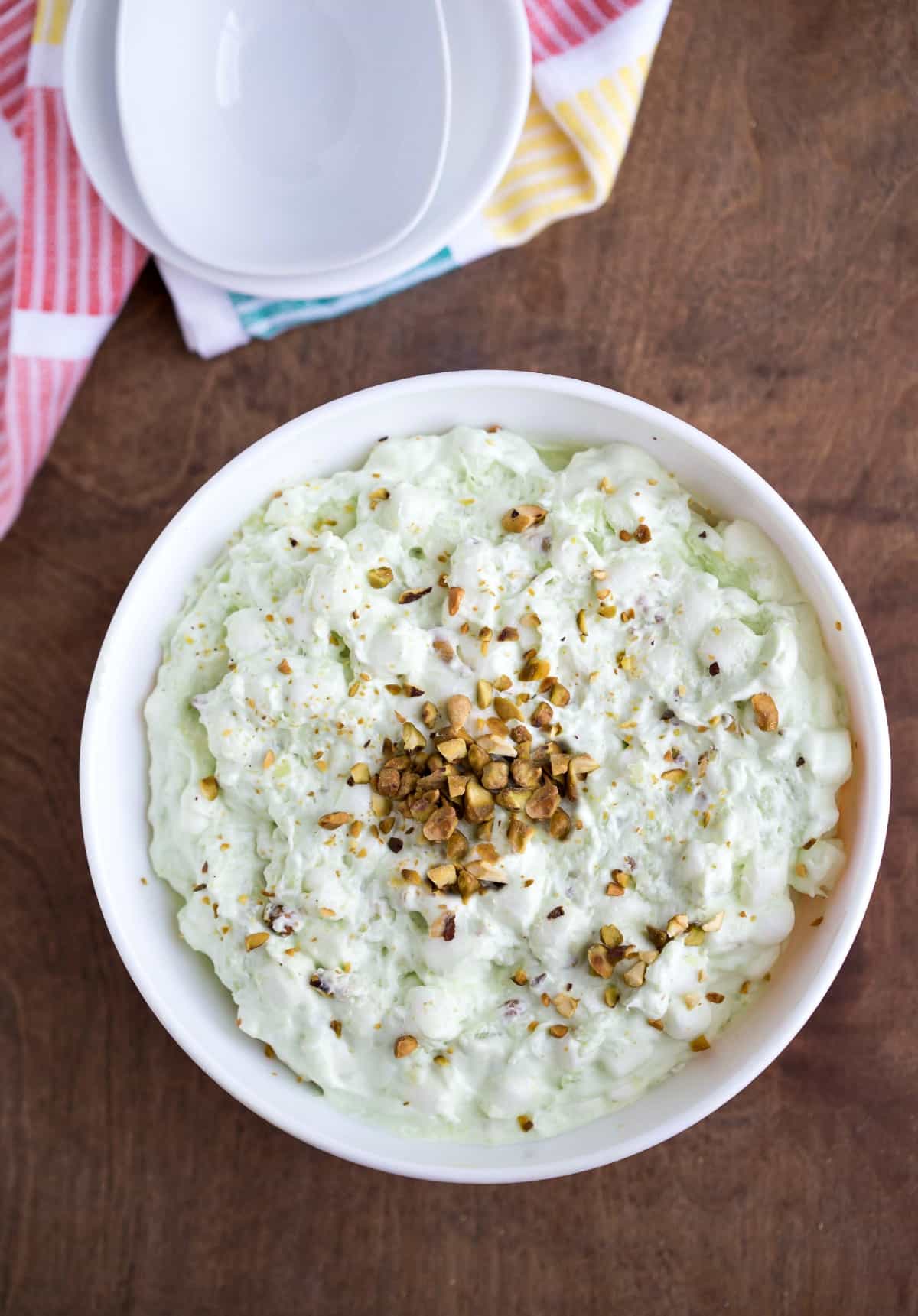 Watergate Salad in a white bowl topped with chopped pistachios