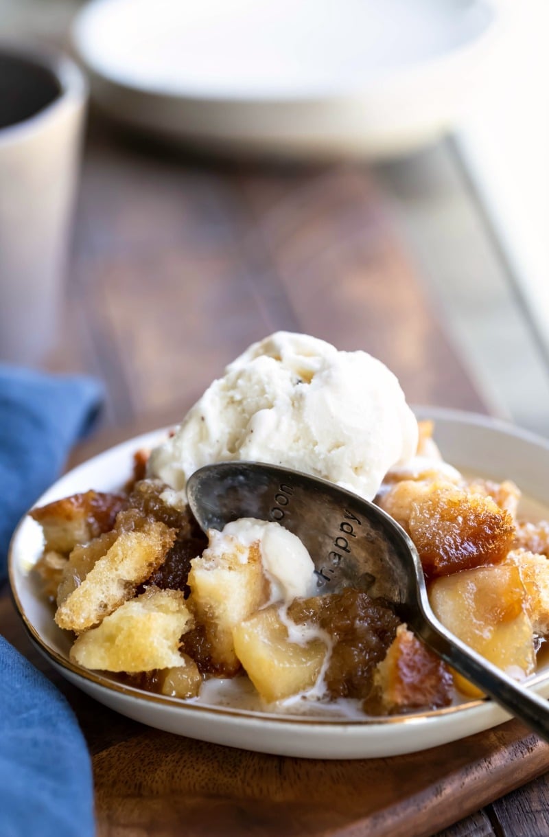 Apple brown betty in a white dish with a silver spoon in it