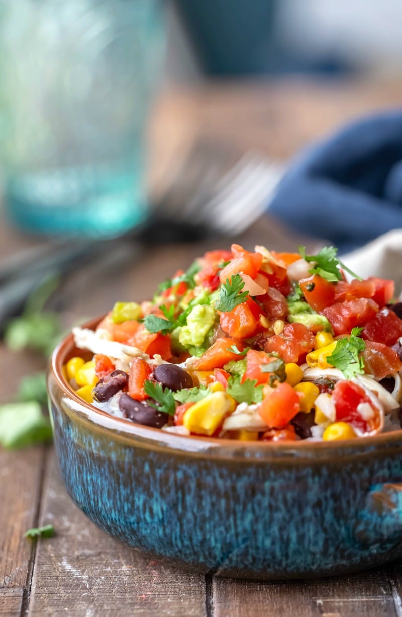 Crock pot mexican chicken in a blue bowl topped with pico de gallo