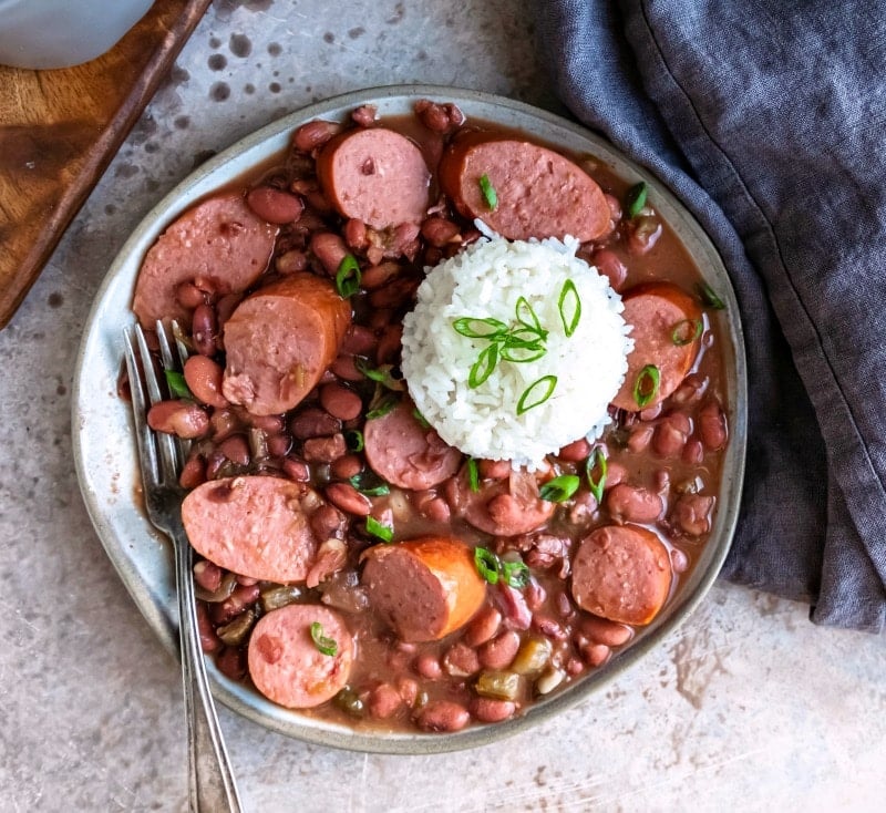 Blue dish with crock pot red beans and rice next to a linen napkin