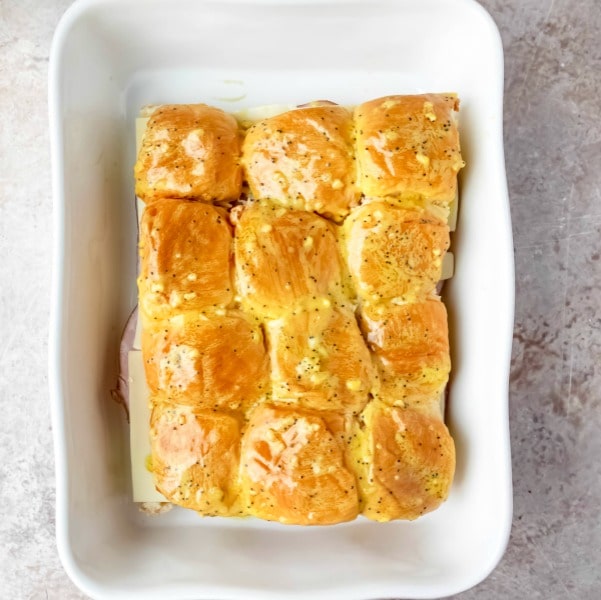 unbaked ham and cheese sliders in a white baking dish