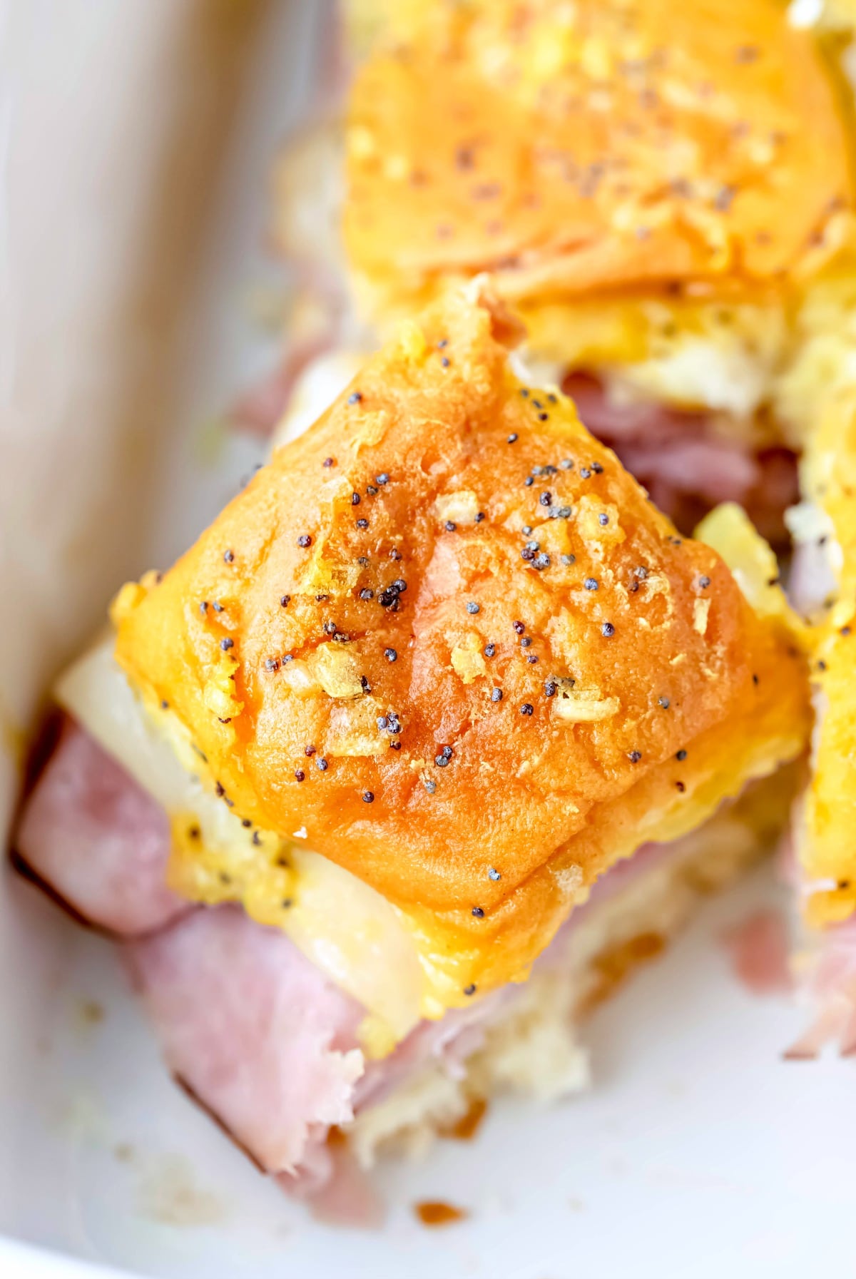Overhead picture of a baked ham and cheese slider in a white baking dish
