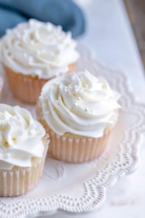 White cupcakes with white frosting on a white plate