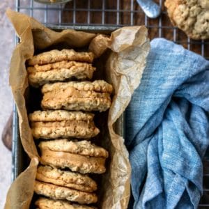 Stack of oatmeal cookies with peanut butter filling in a tin container