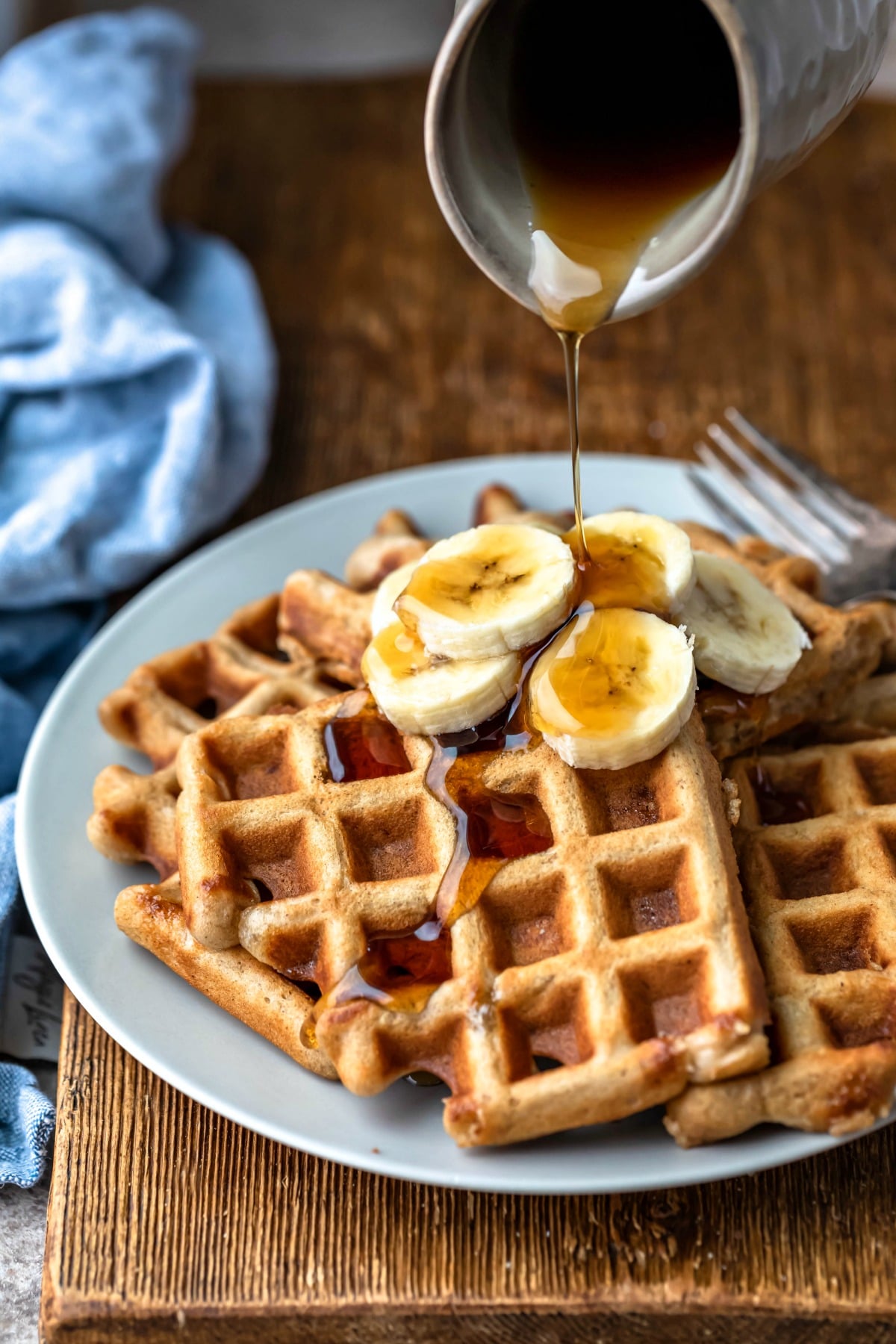 Banana Bread Waffle Recipe Plate of banana bread waffles next to a blue linen napkin