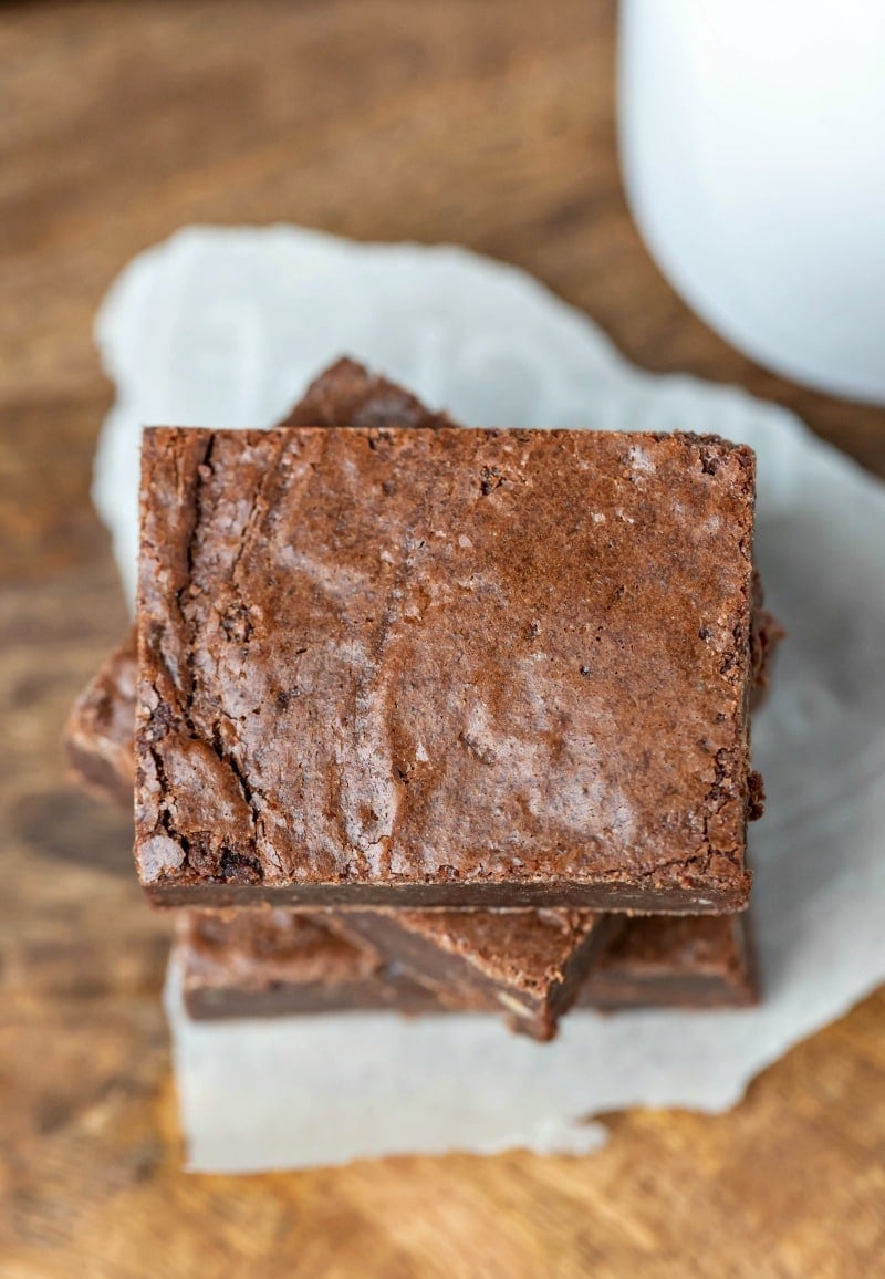 Stack of fudgy brownies on a piece of parchment paper