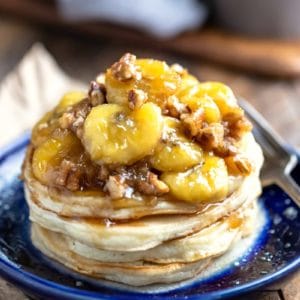 Stack of vanilla pancakes with caramelized bananas on a blue plate