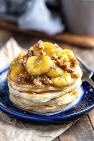 Stack of vanilla pancakes with caramelized bananas on a blue plate