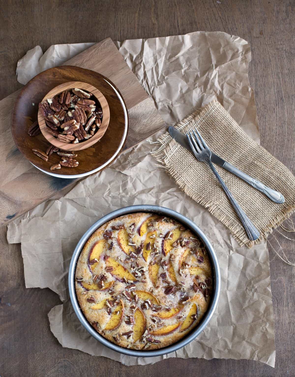 Peach cake in a metal pan on a piece of brown parchment paper