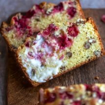 Two slices of cranberry nut bread on a wooden cutting board