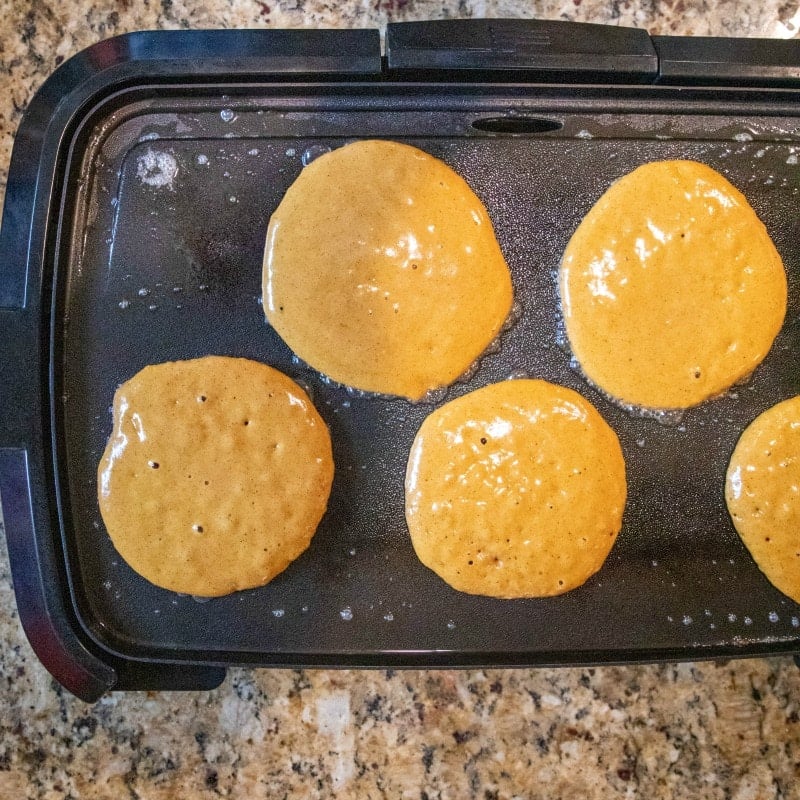 Gingerbread pancakes cooking on a griddle.