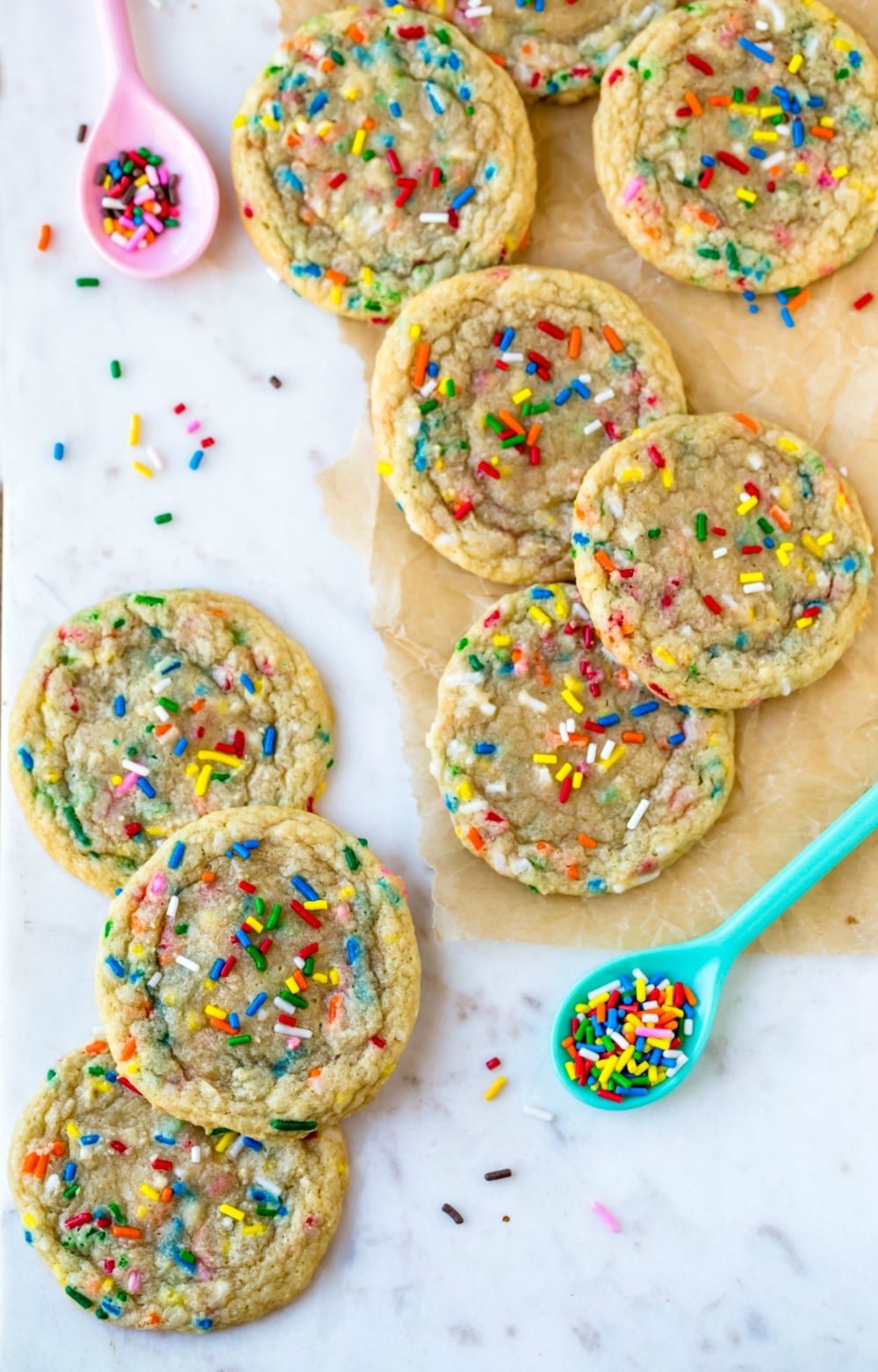 Homemade funfetti cookies next to spoons with sprinkles