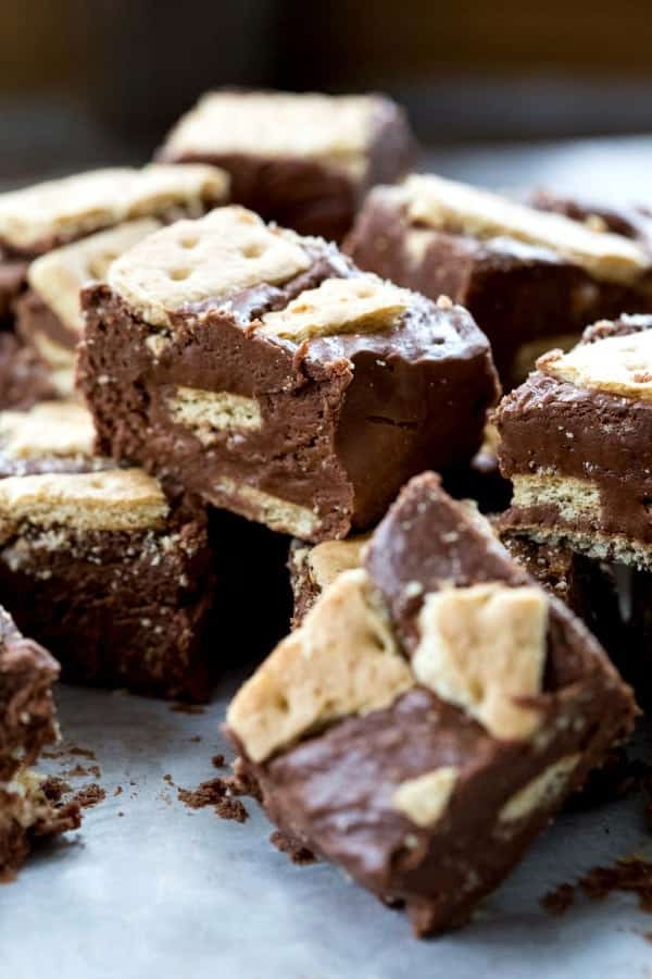 Stacked pieces of s'mores fudge on a piece of white parchment paper. 