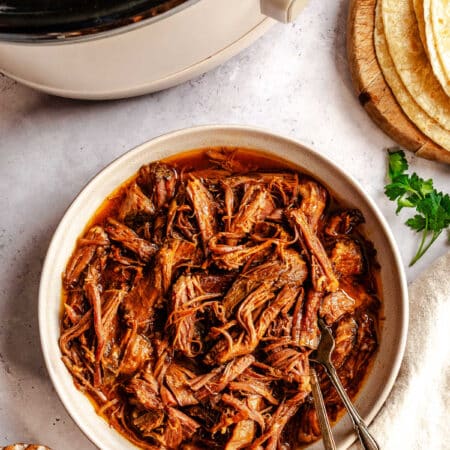 A dish of slow cooker pineapple chipotle beef in a dish with two forks in it.