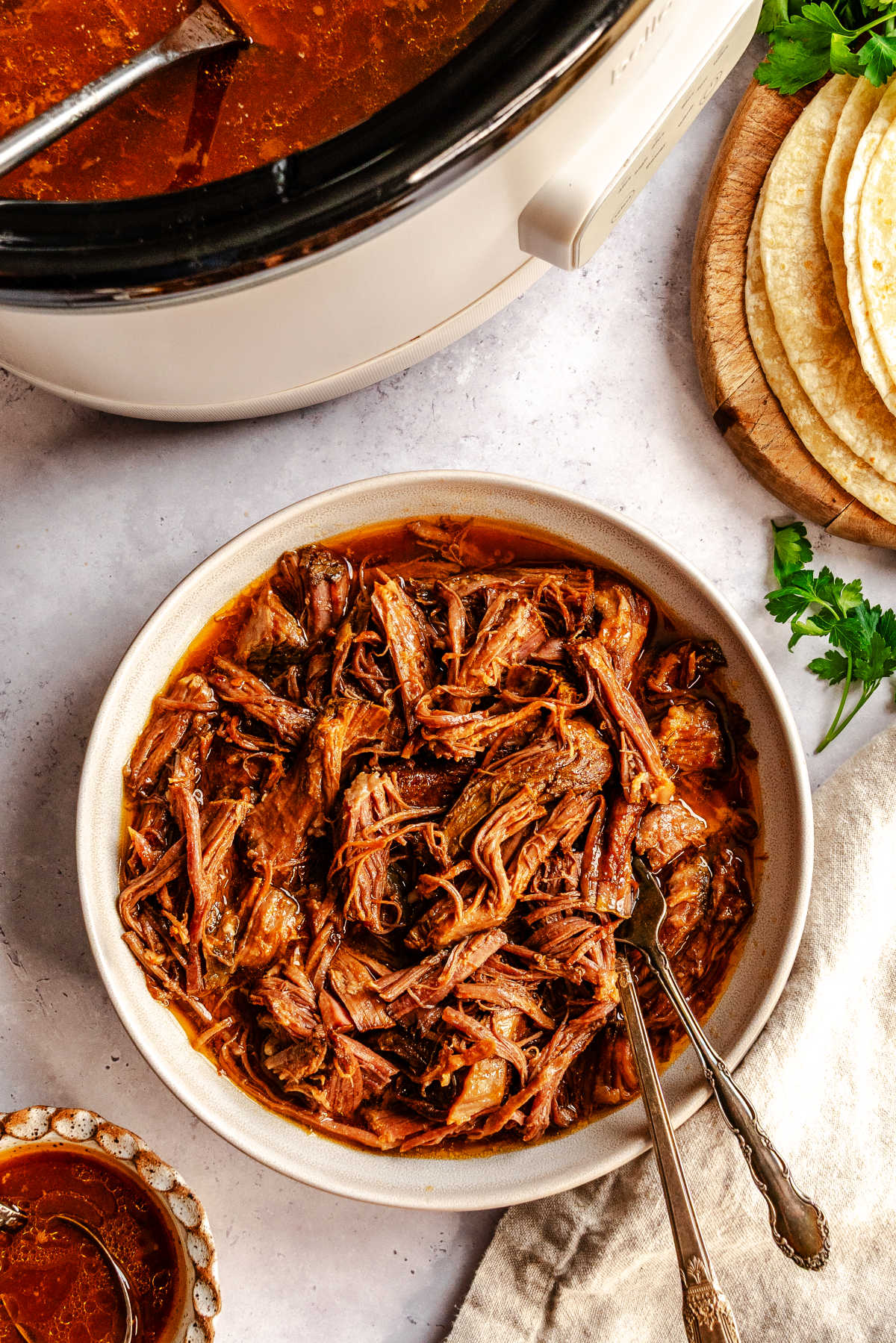 A dish of slow cooker pineapple chipotle beef in a dish with two forks in it.