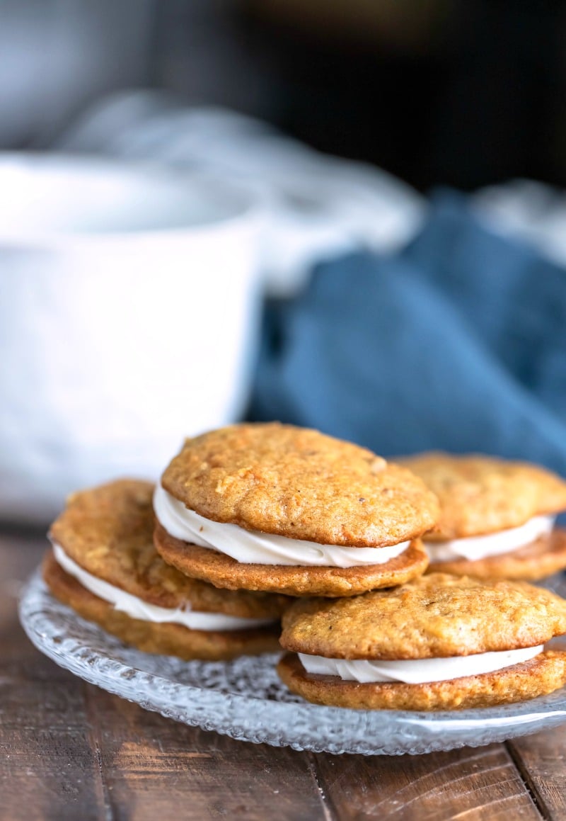 Four carrot cake sandwich cookies on a glass plate