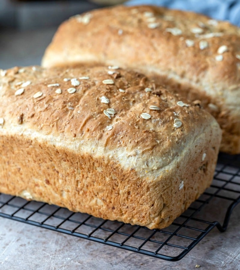 Two loaves of multigrain bread on a wire cooling rack