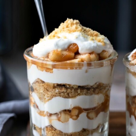 No bake apple pie parfait in a glass jar on a wooden cutting board