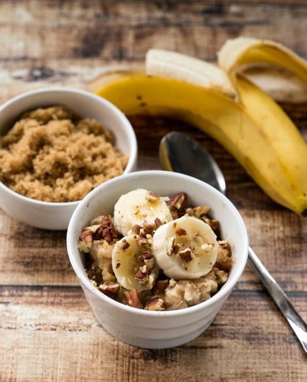 A bowl of Overnight Crockpot Banana Bread Oatmeal topped with fresh banana slices and chopped pecans