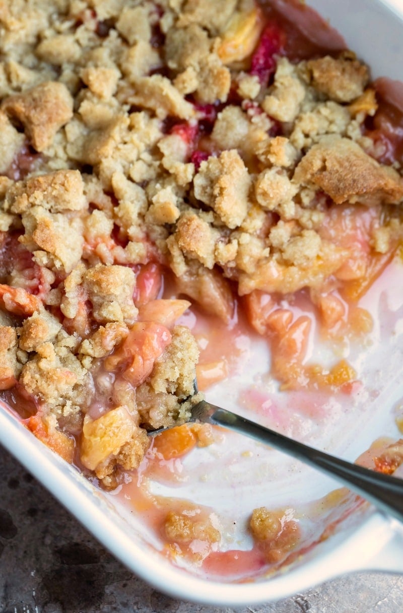 White baking dish with peach crumble in it
