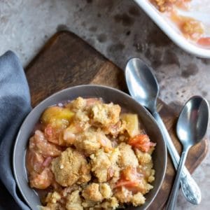 Dish of peach crumble on a wooden cutting board