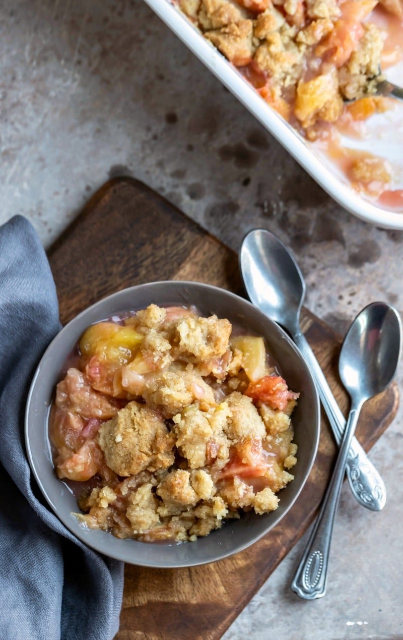 Dish of peach crumble on a wooden cutting board