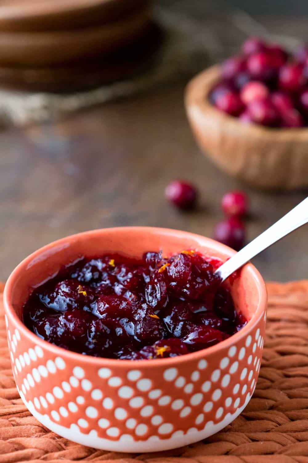 Maple Cranberry Sauce in an orange and tan bowl with a silver spoon