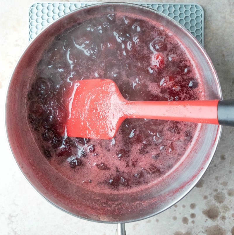 Steaming hot maple cranberry sauce in a silver saucepan