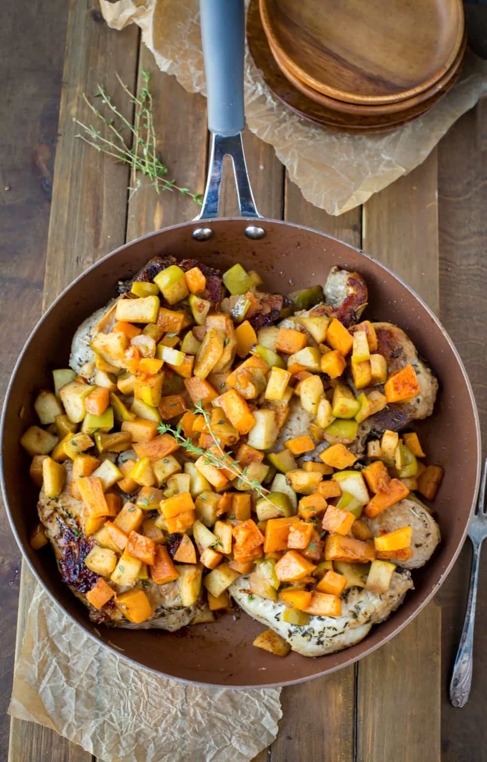 Pork Chops with Cinnamon Apples and Butternut Squash in a copper skillet topped with thyme