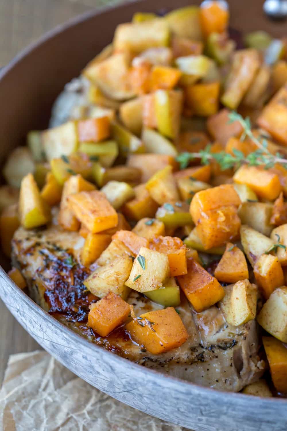 Pork Chops with Cinnamon Apples and Butternut Squash in a skillet on brown parchment paper